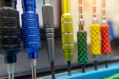 Colored screwdrivers stand in a row on the workshop desktop. Stock Photos