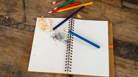 Colored, sharpened pencils on a white notebook with a sharpener, copy space Stock Photos