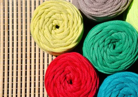Colored skeins of thread for weaving macrame on a wooden surface. Stock Photos