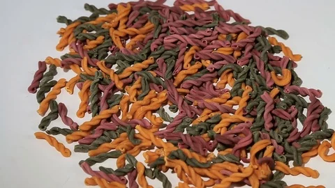Colored spiral pasta. Uncooked pasta rotation on a white background. Delicious Stock Footage 75575255