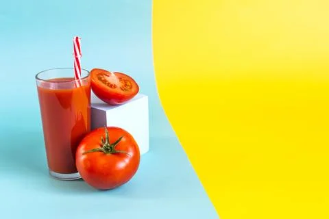 Colored split background with tomato juice, blue podium and tomatoes Stock Photos
