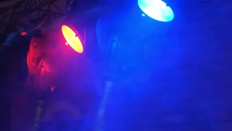 Colored spotlights shining through smoke in a nighttime event hall Video stock 342134708