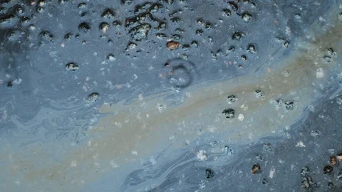 Colored spots from gasoline move to flow with water. asphalt. rain. Stock Footage 123360594