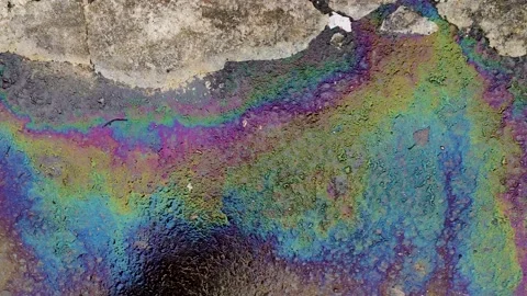 Colored spots from gasoline move to flow with water. asphalt. rain. stream. Stock Footage 237634356
