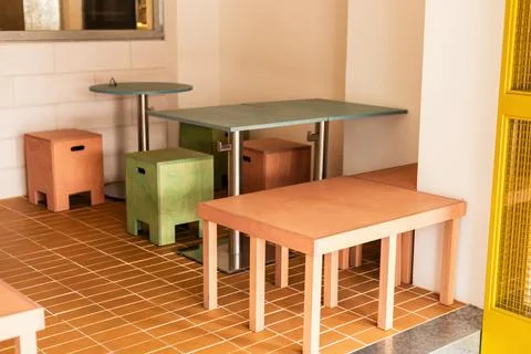 Colored stools and tables are arranged in a small cafe area. The space featur Stock Photos