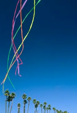 Colored streamers floating in the sky above palm trees 스톡 사진