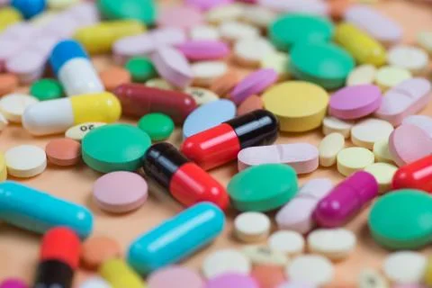 Colored tablets and pills on a orange background Stock Photos