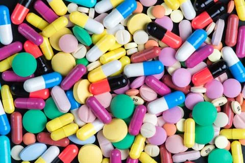 Colored tablets and pills on a orange background Stock Photos
