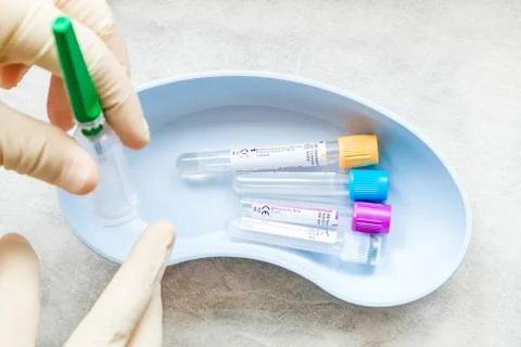 Colored test tubes are in a container. A gloved hand holds the device Stock Photos