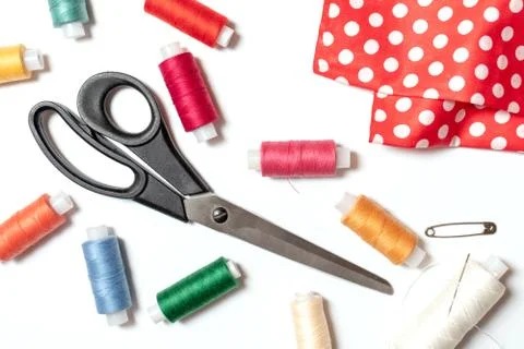 Colored thread coils, scissors, pin and fabric on white background, sewing, h Stock Photos