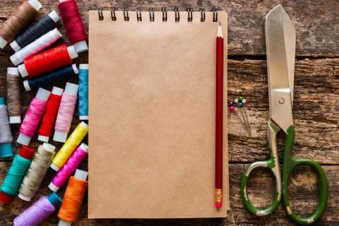 Colored thread, scissors and notepad for notes on the wooden background 스톡 사진