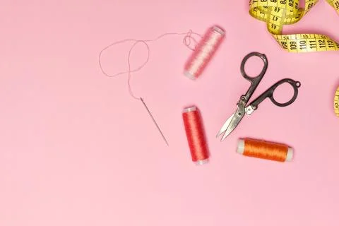 Colored thread spools and sewing accessories on a pink background in a top vi Foto stock