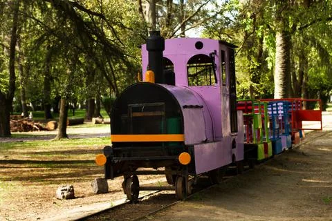A colored train to carry childrens on train tracks in a park Foto stock