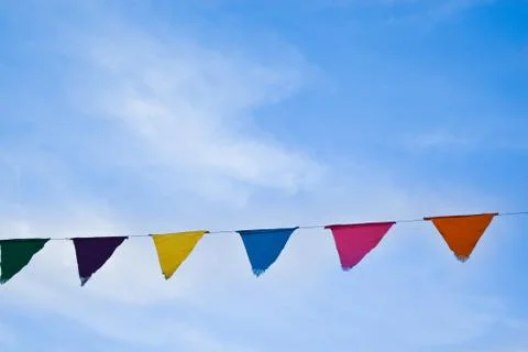 Colored triangular flags on bright blue sky background Stock Photos