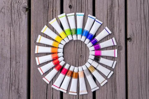 Colored tubes of paint in shape of circle on wooden background top view Fotos Stock