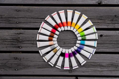 Colored tubes of paint in shape of circle on wooden background top view Foto stock
