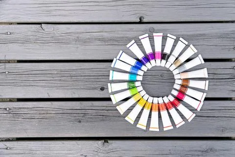 Colored tubes of paint in shape of circle on wooden background top view Foto stock