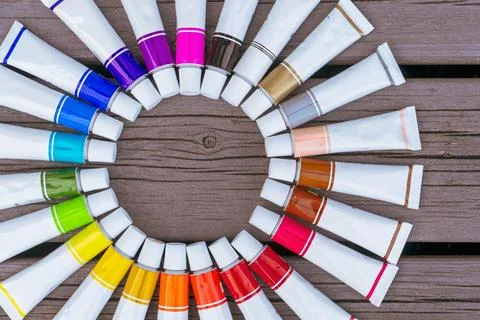 Colored tubes of paint in shape of circle on wooden background top view Stock Photos