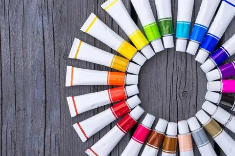 Colored tubes of paint in shape of circle on wooden background top view 库存照片