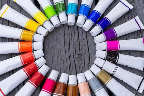 Colored tubes of paint in shape of circle on wooden background top view 库存照片