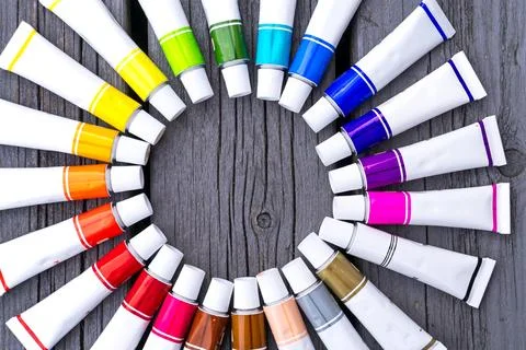 Colored tubes of paint in shape of circle on wooden background top view 库存照片