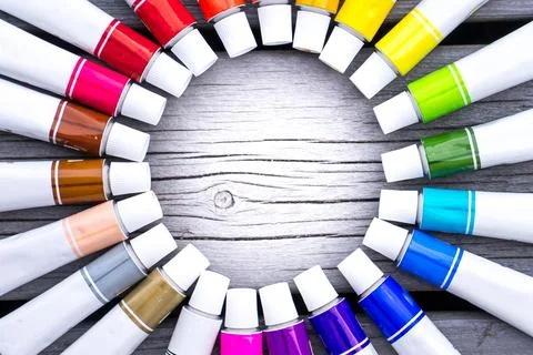 Colored tubes of paint in shape of circle on wooden background top view Foto stock