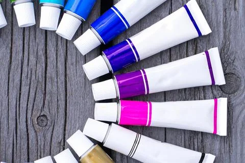 Colored tubes of paint in shape of circle on wooden background top view 库存照片