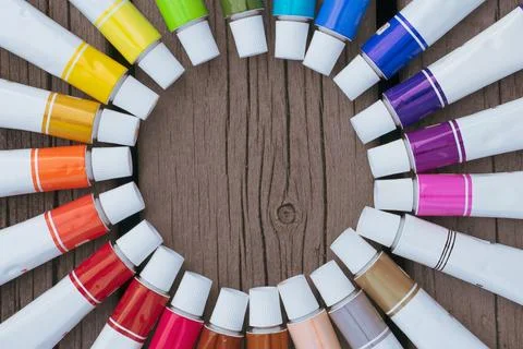 Colored tubes of paint in shape of circle on wooden background top view 库存照片