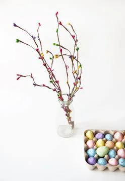 Colored willow branch and colored eggs in a cage of eggs. Stock Photos
