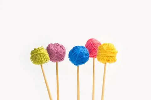Colored wool balls on knitting needles on a white background Foto stock