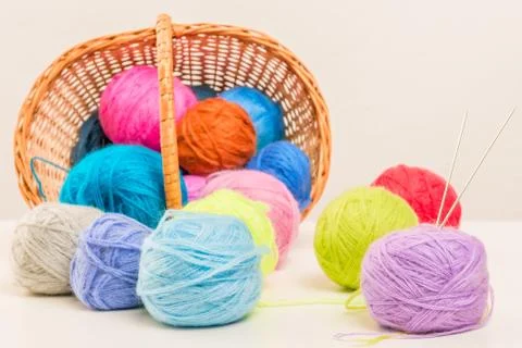 Colored woolen thread crumbled from wicker basket close up on a white backgro Stock Photos