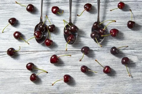 Colorfiul pattern of three spoons with red juicy ripe cherries with berries on a Fotos de archivo