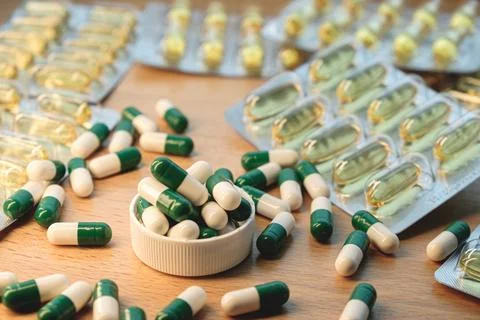 Colorful array of capsules and supplements scattered on wooden surface Stock Photos
