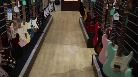 A colorful array of electric guitars lines both sides of the aisle, showcasing a Stock Footage 294706669