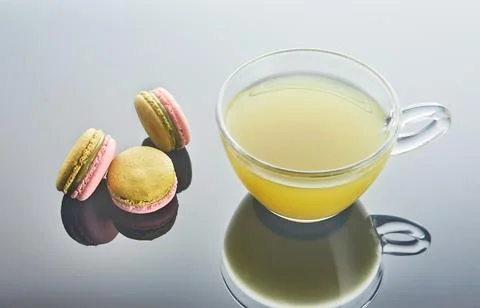 A colorful array of macarons encircle a steaming cup of coffee Stock Photos