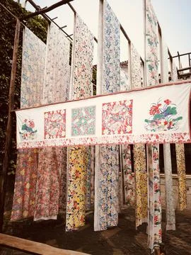 Colorful array of silk fabrics hanging from wooden poles in a vibrant display Foto stock