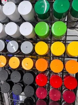 Colorful array of spray paint cans organized on a metal rack Stock Photos
