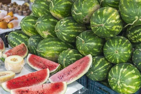 A colorful array of whole and sliced watermelons is showcased at a lively mar Stock Photos