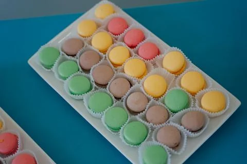 Colorful assortment of macarons arranged on a white platter with vibrant Stock Photos