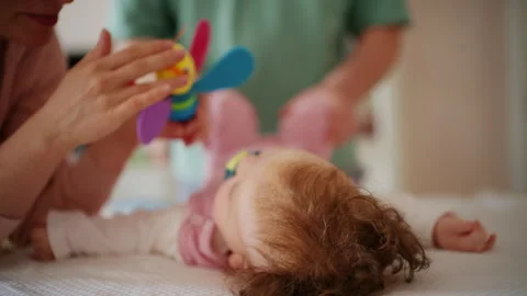 A colorful baby rattle is gently presented to an infant, while caregiver is Vidéo 336928811