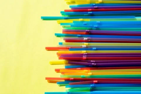Colorful background. Flatlay. Multicolored drinking cocktail straws on yellow Stock Photos