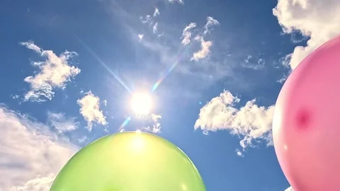 Colorful balloons drifting under bright sun with clouds Stock-Footage 324504334