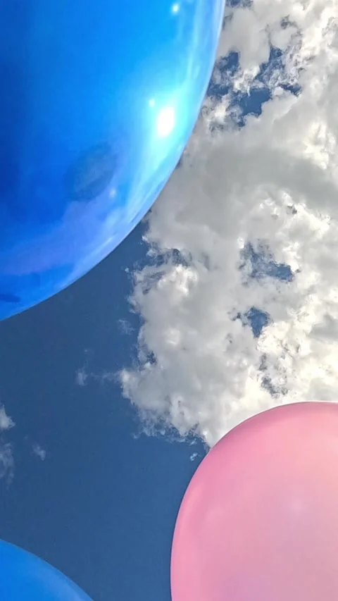 Colorful balloons floating gently below bright clouds Video stock 321385384