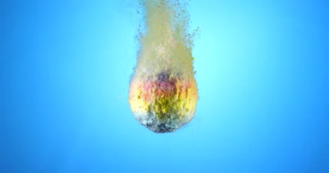 Colorful bath bomb falling down into clean water against blue background. Filmed Stock Footage 151854267
