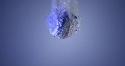 Colorful bath bomb falling down into clean water against blue background. Filmed Stock Footage 152815594