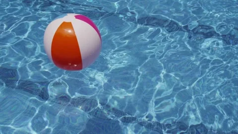 Colorful beach ball floating in clear blue swimming pool water Stock Footage 333485159