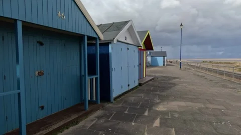 Colorful beach huts stood in a line along the seafront with sandy beach and.. Stockbeeldmateriaal 240285857