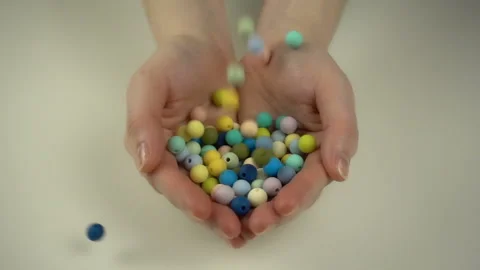 Colorful beads falling on the hands in slow motion. Stock Footage 103602809
