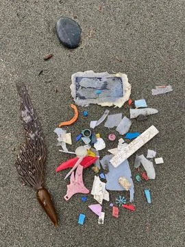 Colorful Bits of Plastic Washed Up on Sandy Beach Stock Photos