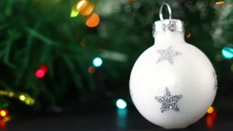 Colorful blinking lights behind white little Christmas ornament Stock Footage 142877243